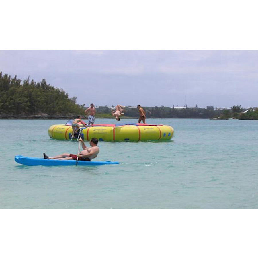 Several young adults playing on the Island Hopper 25' Giant Jump Water Trampoline out on the lake while a kayaker goes by. 