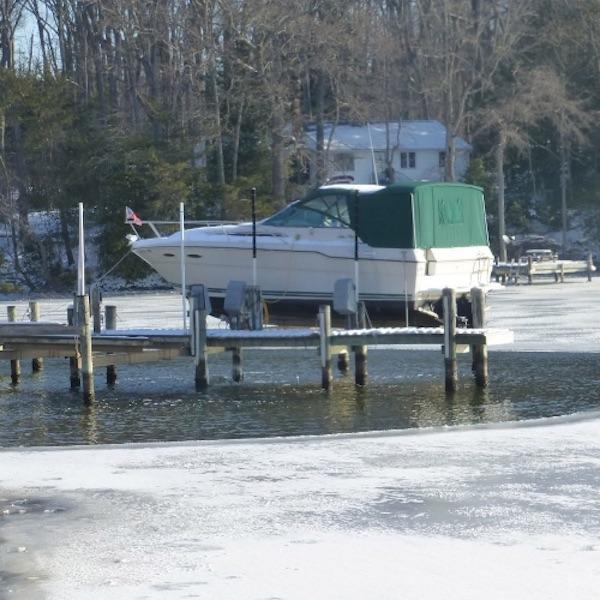 Kasco De Icer is shown as a display picture on a white background.  Kasco De Icers have a silver base similar to a paint can with a white Kasco Ice Eater logo on the front.  Coming out of the top is short extension with a propeller attached.  There is a circular cage with bars around the propeller, like the propeller is in jail type of look.  There are 2 mooring ropes attached and rolled up next to the dock de icer for sale.  There is a black power cord that is also attached to the Kasco De Icer for Sale.