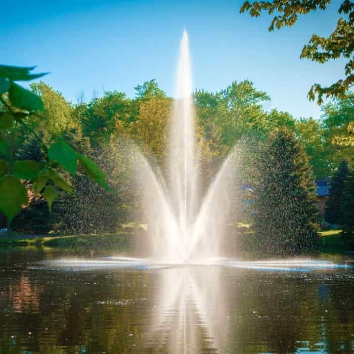 Scott Aerator Atriarch Pond Fountain sits in the middle of pond creating a beautiful spray of water up in the air against green trees in the background.  The Scott Aerator Floating Pond Fountain elegance is on display. This floating fountain is a spectacular sight to see.